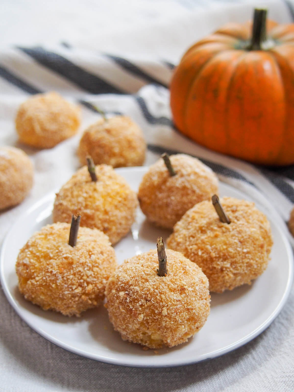plate of baked pumpkin arancini with small pumpkin behind