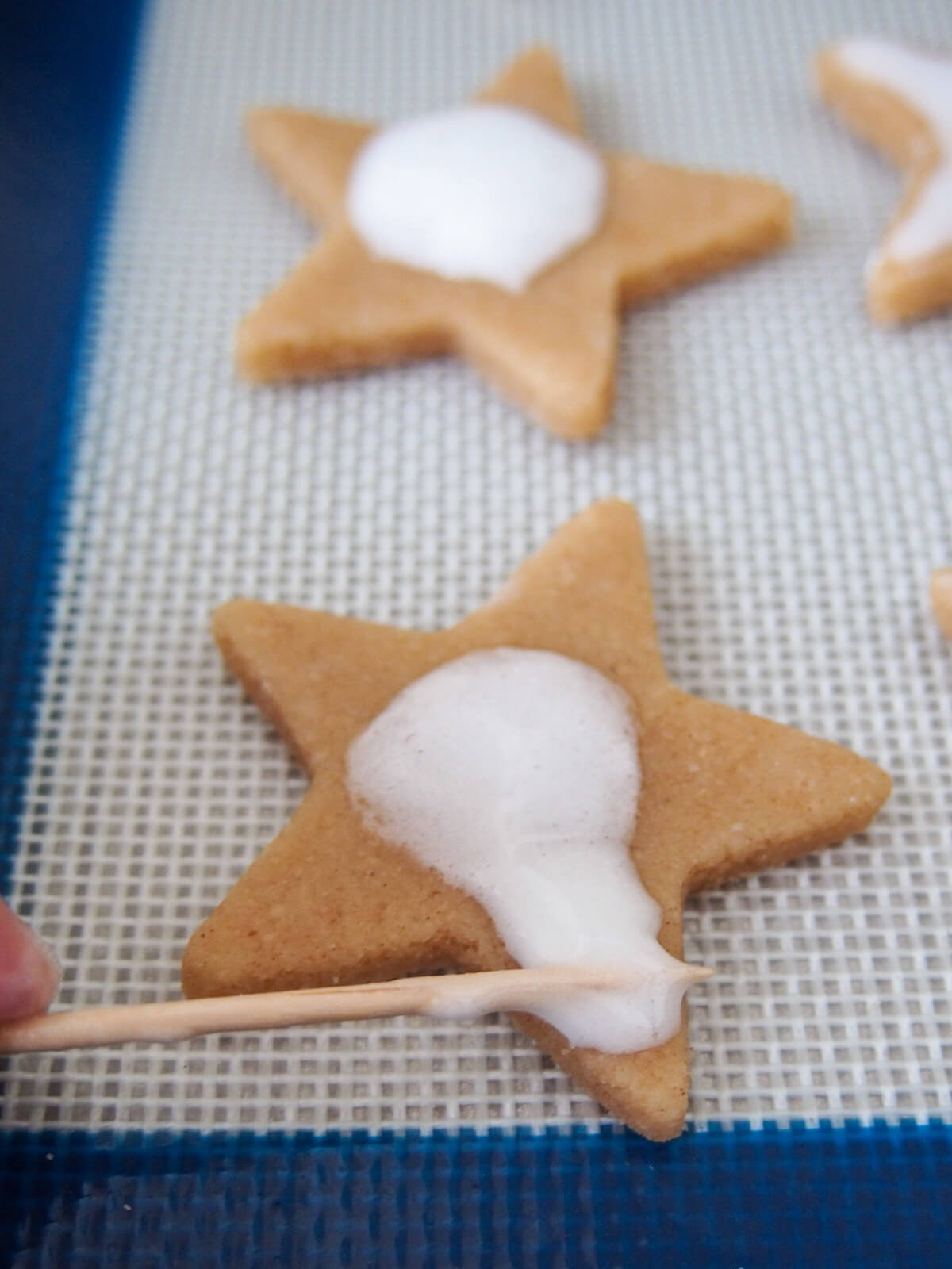 spreading meringue topping over cookie with a cocktail stick