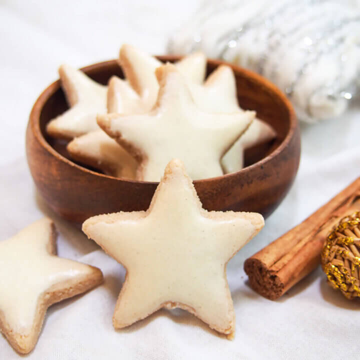 a cinnamon star cookie (zimtsterne) resting on bowl with additional cookies