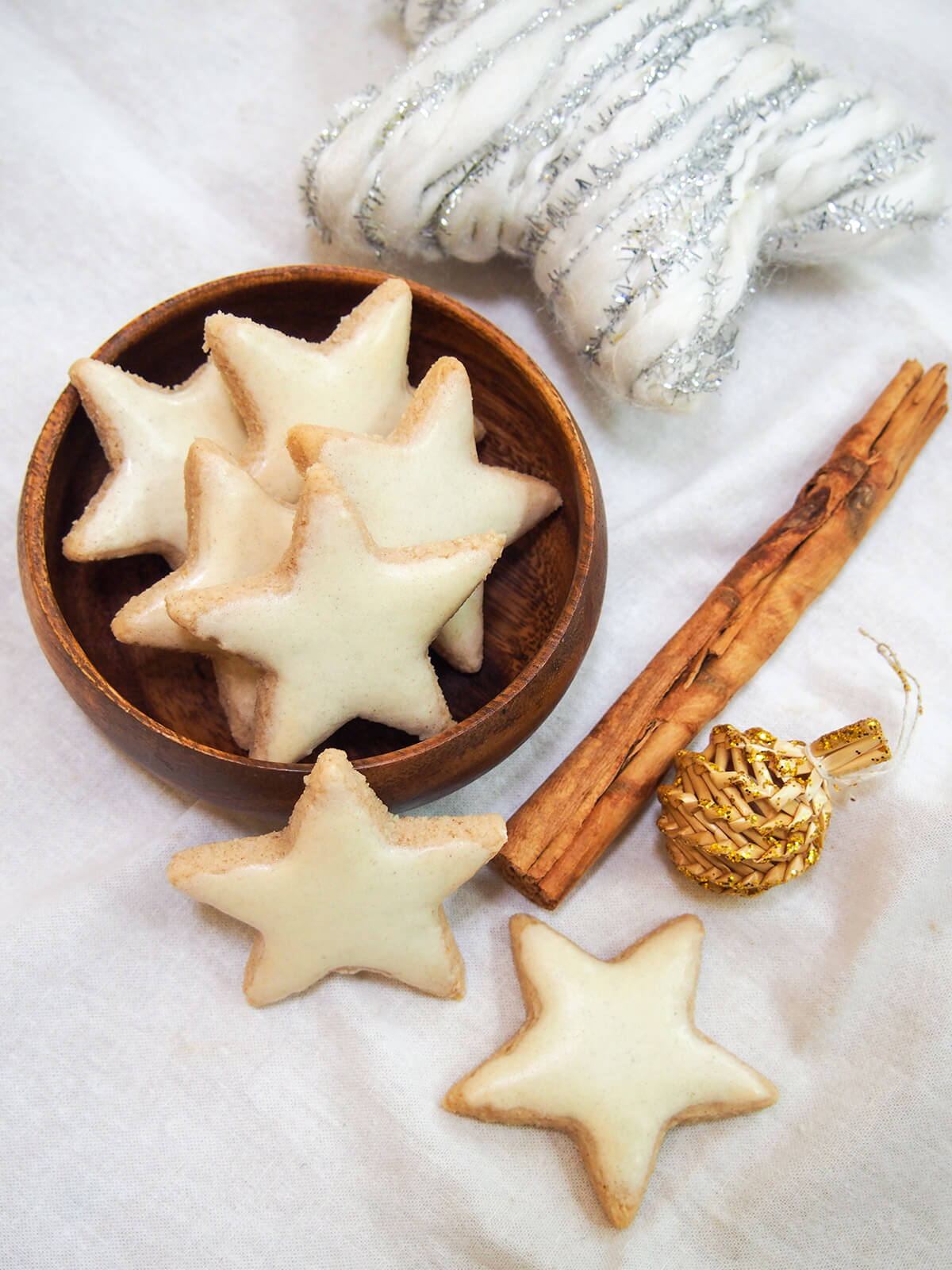 zimtsterne cinnamon star cookies in bowl, cinnamon stick and decorations to side
