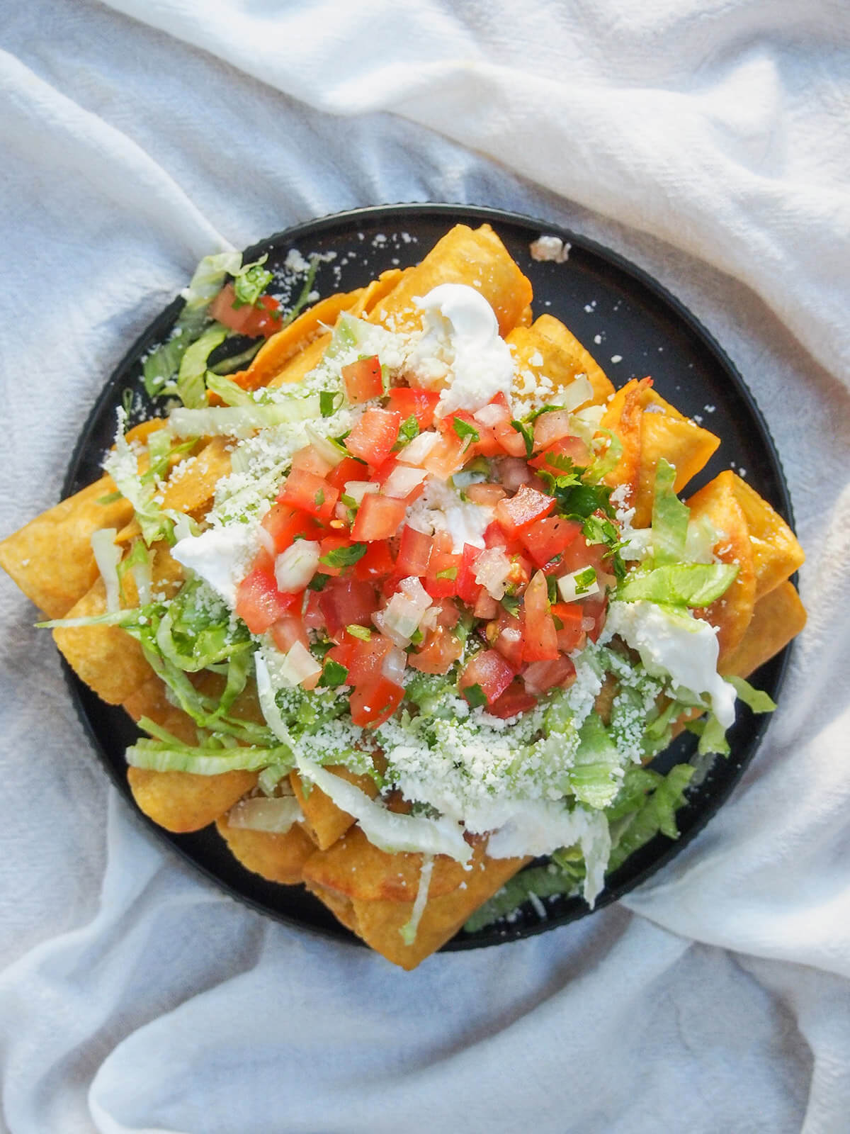 plate of chicken flautas from overhead with lettuce and pico de gallo on top