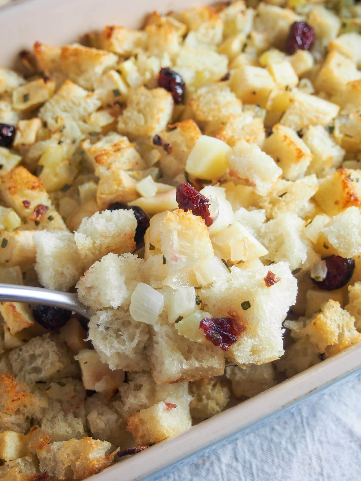 spoon scooping some cranberry apple stuffing from dish