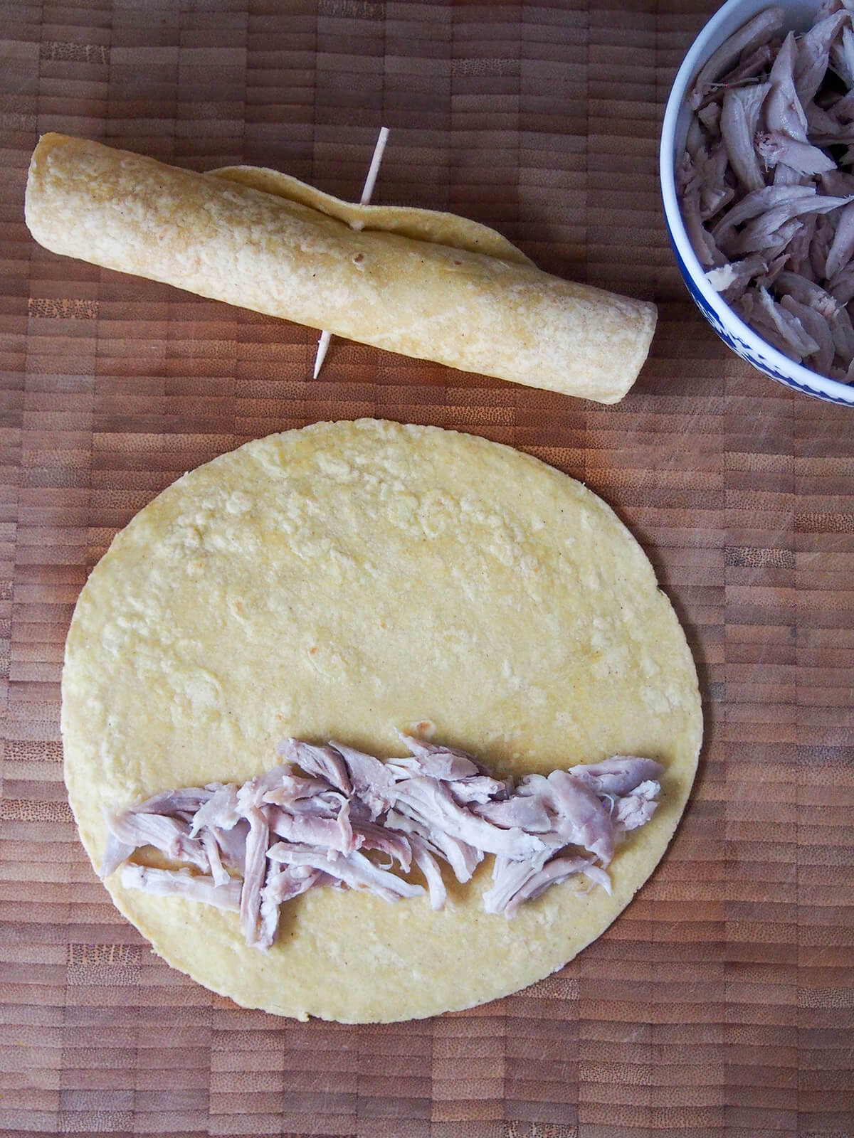 some shredded chicken on top of a tortilla with a formed flauta above