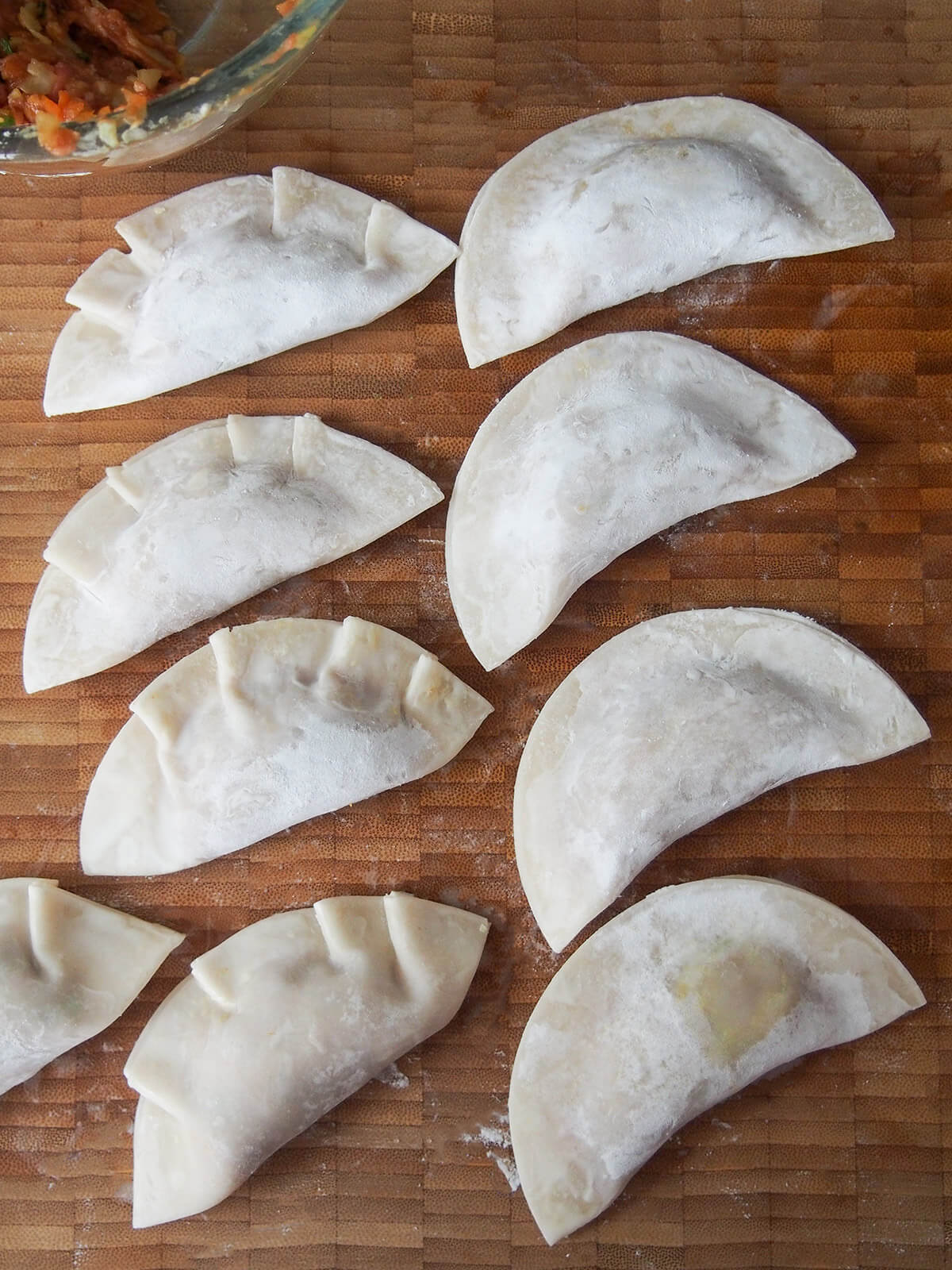 formed dumplings on board, some with pleats and some flat
