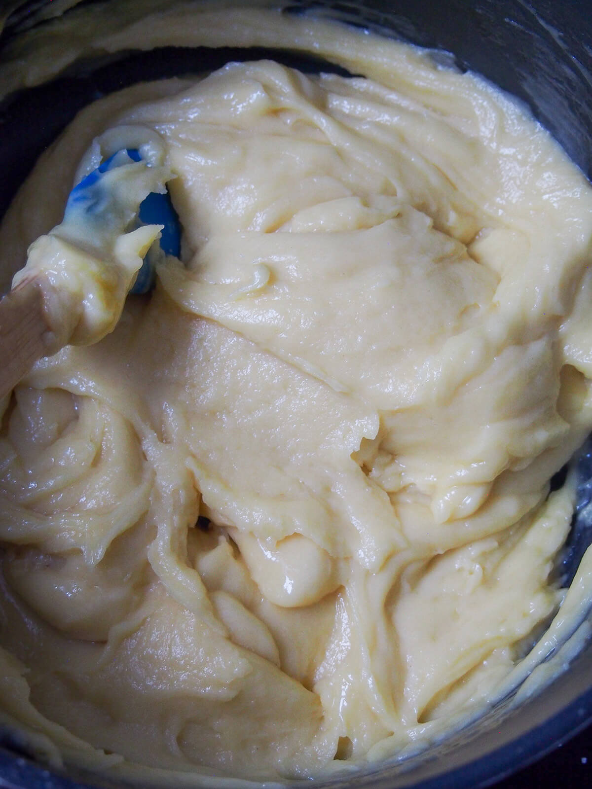 dough for gougeres after adding eggs but before cheese gougere dough in pot after mixing in eggs before adding cheese