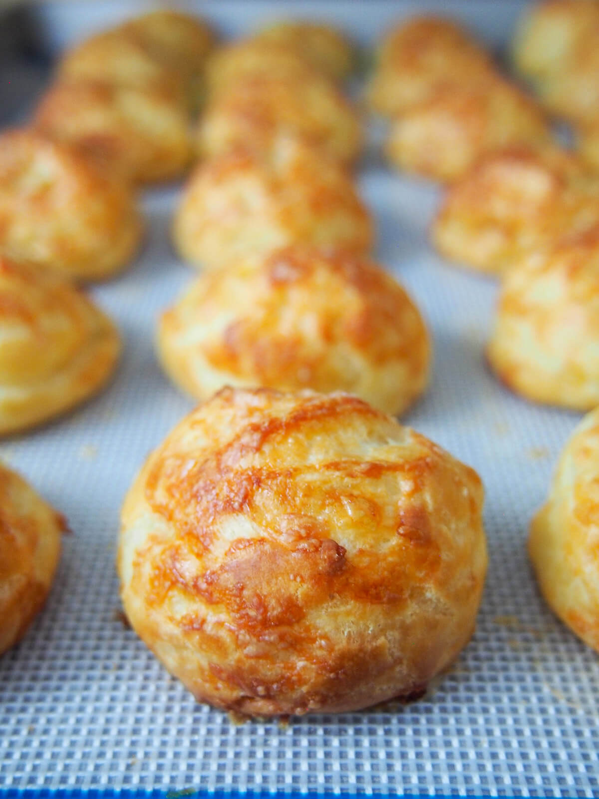 gougeres (French cheese puffs) just out of the oven rows of gougeres cheese puffs on baking sheet just out oven