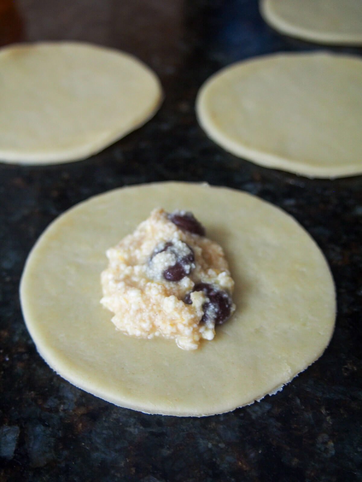 some of ricotta chocolate filling on circle of dough with more dough circles behind