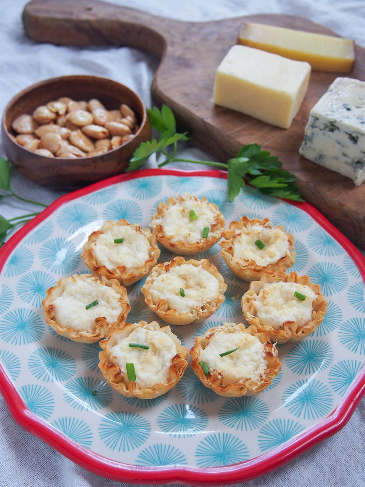 plate of crab phyllo cups with cheese board and bowl with almonds behind