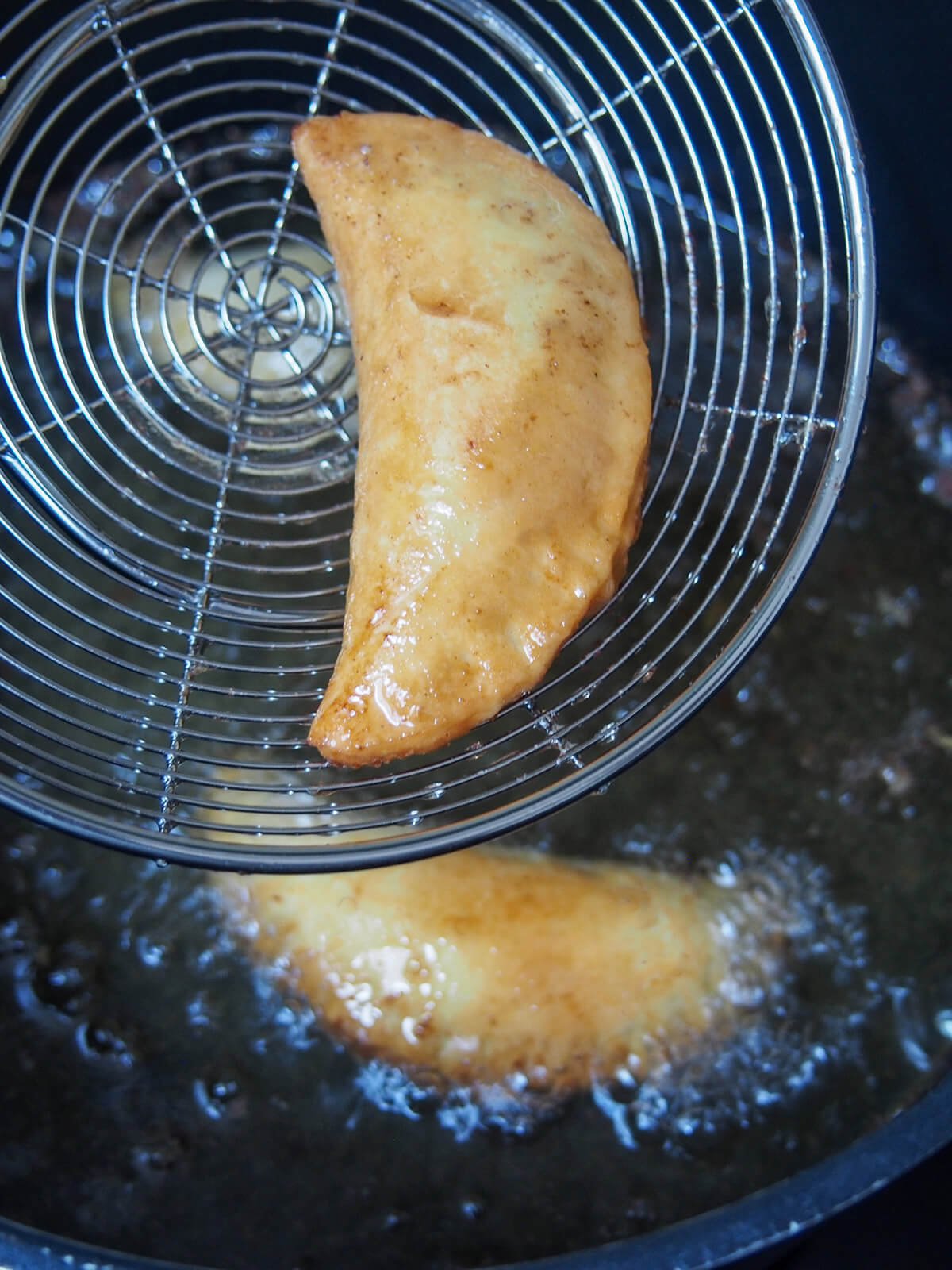 lifting a cooked sweet ravioli from the cooking oil