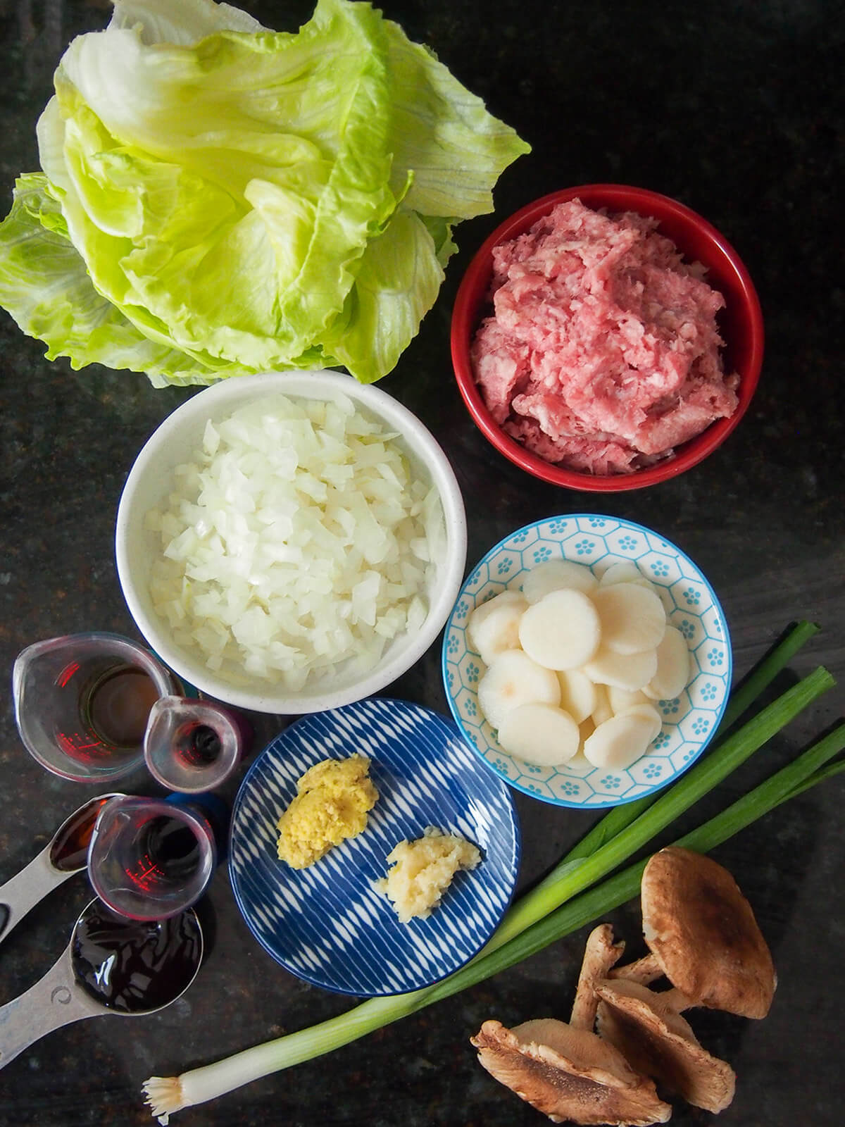 bowls with pork, onion, water chestnuts, garlic and ginger with lettuce above and mushrooms below