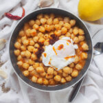 bowl of lablabi chickpea stew with spoon to side, lemon in corner