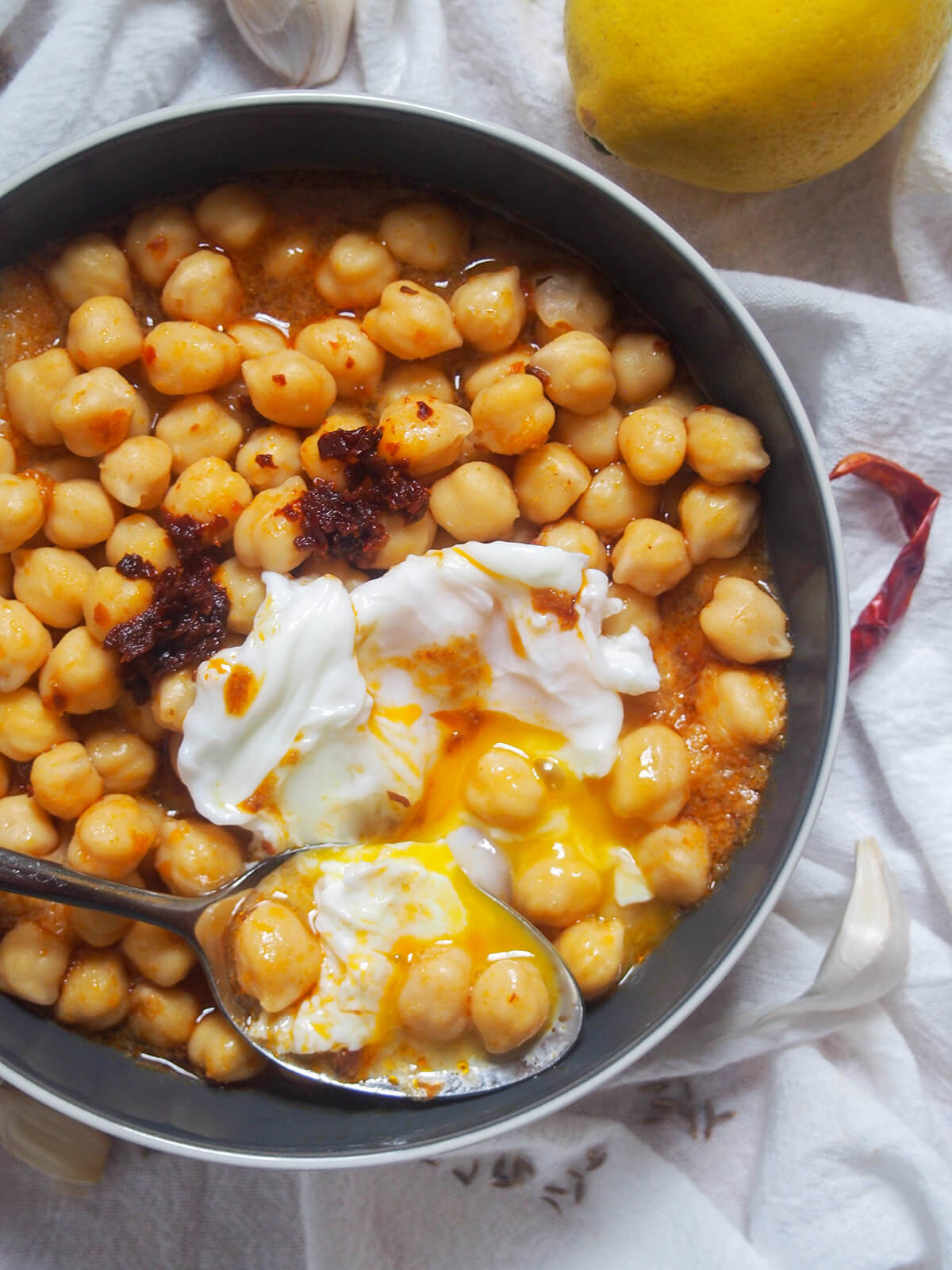 spoon at bottom of bowl of lablabi with some chickpeas and egg on it