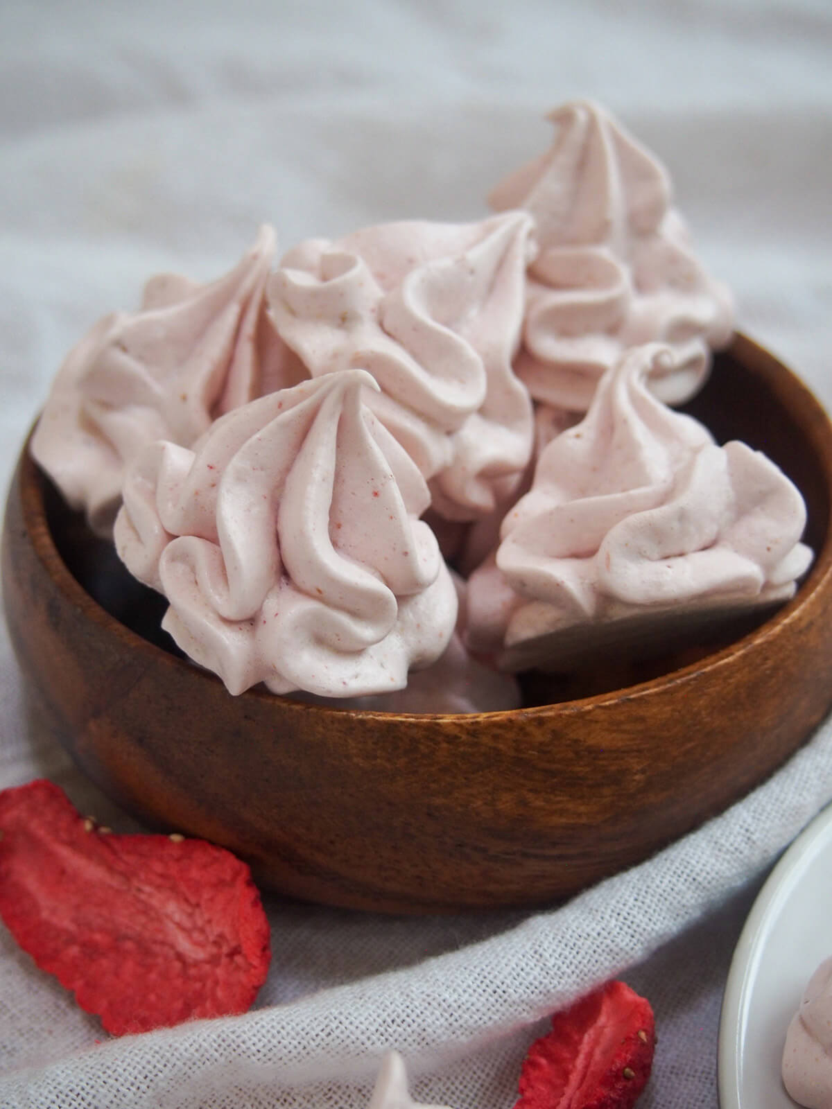 small wooden bowl with strawberry meringue cookies