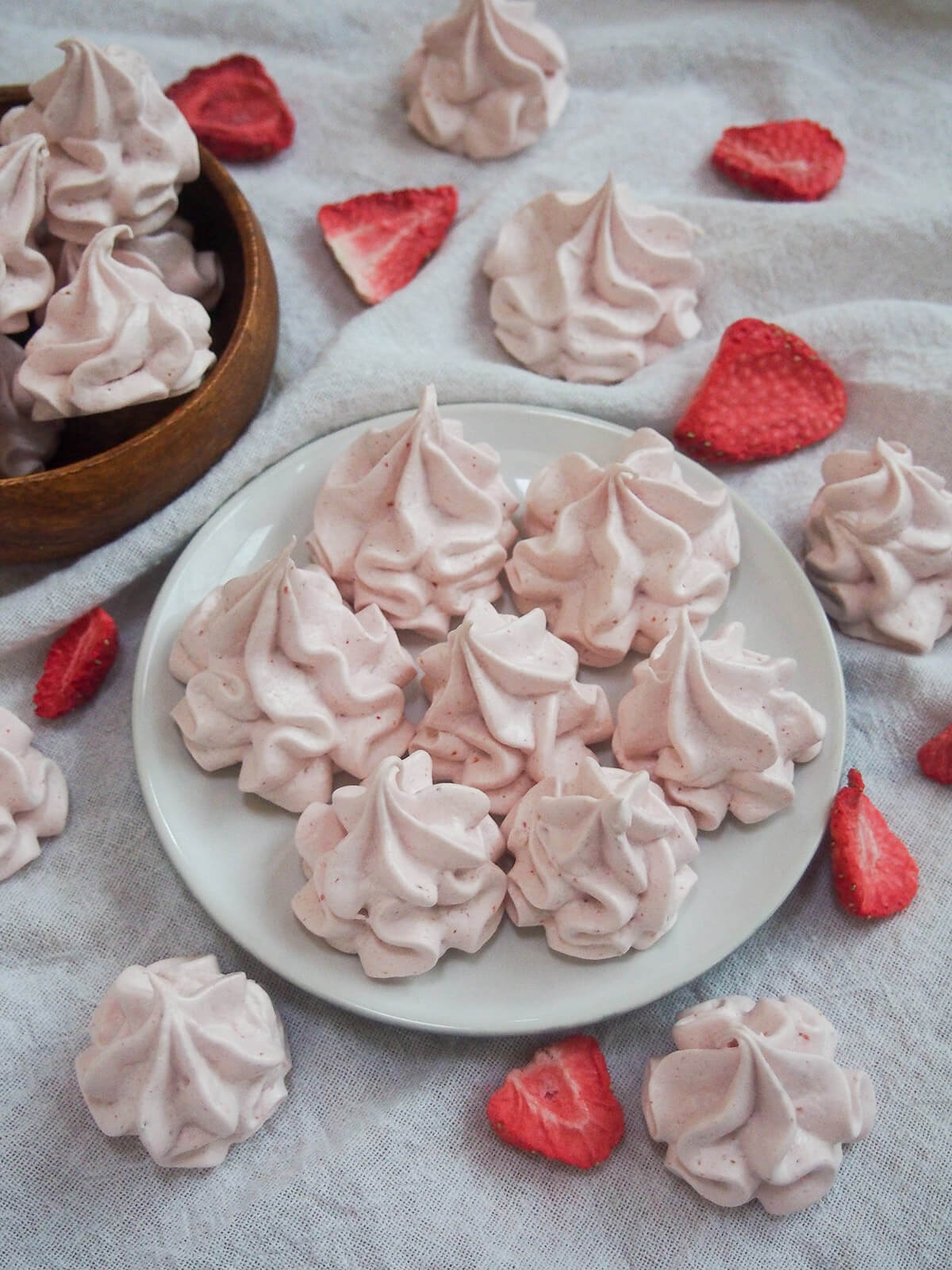 plate of strawberry meringue cookies with bowl in corner to side
