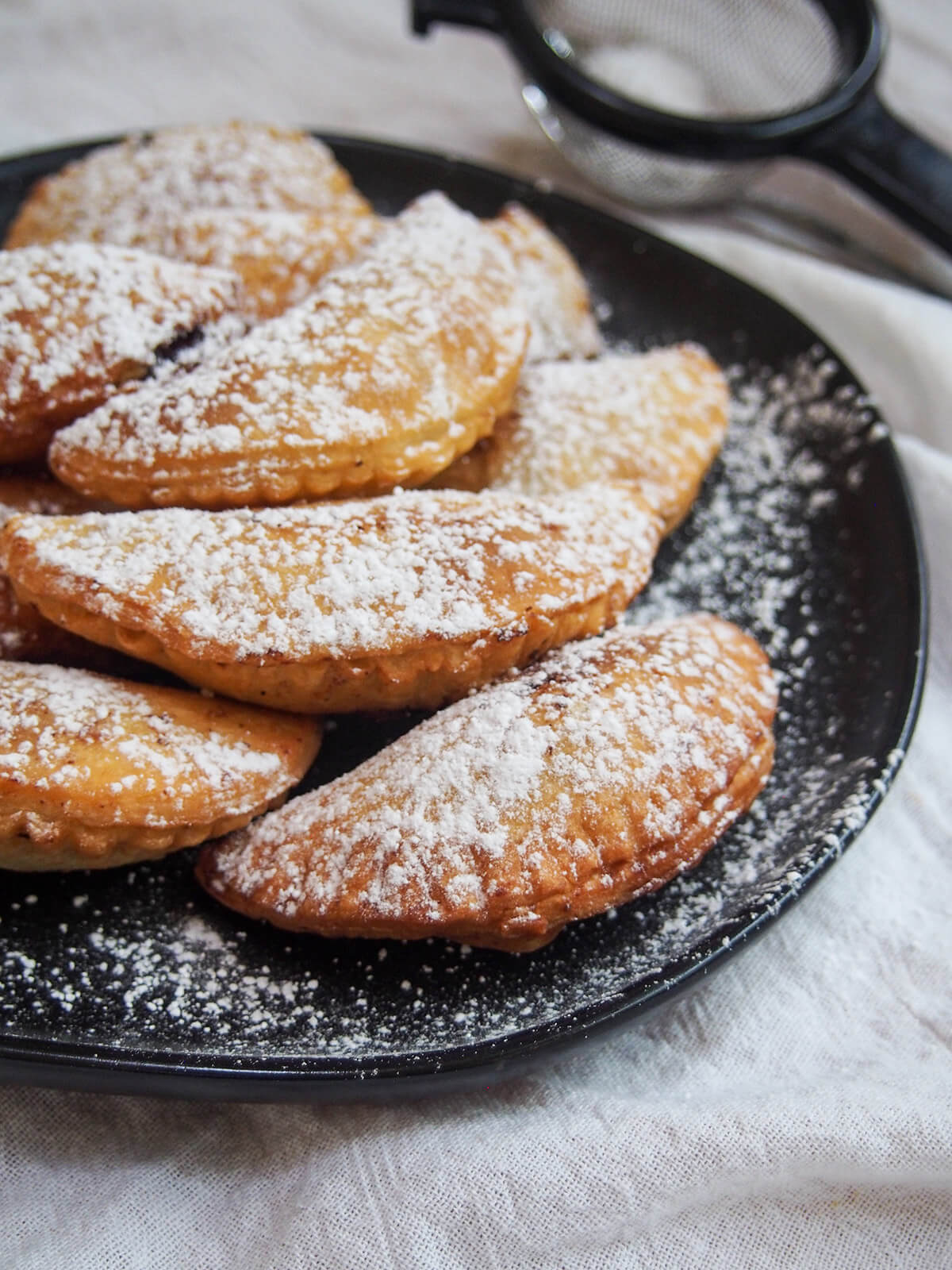 side view of plate of ravioli dolci (sweet ravioli) dusted with sugar