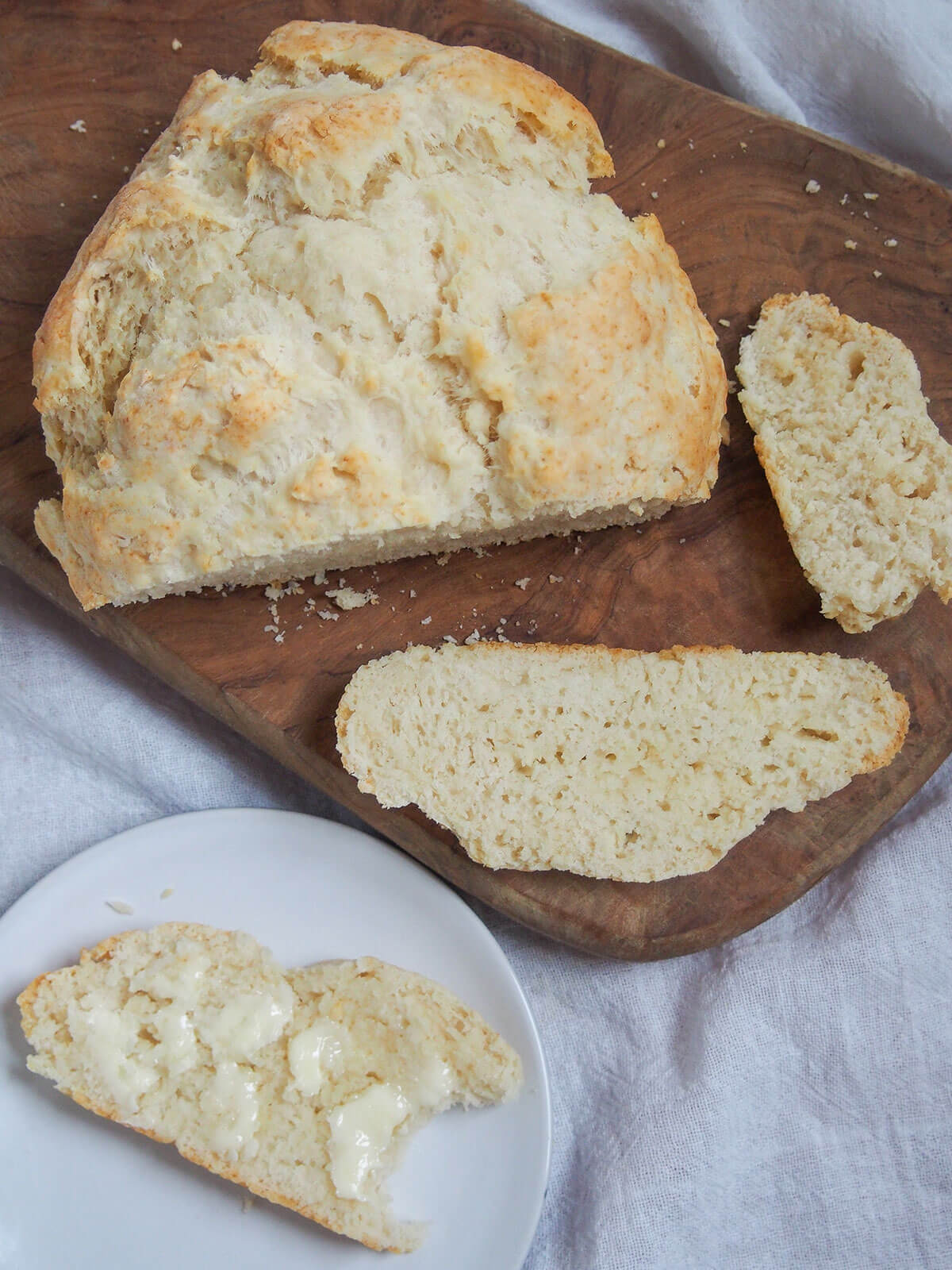 Australian damper is a type of quick bread that's really easy to make. Traditionally cooked in the fire, it's just as easy at home. Great with sweet or savory toppings. overhead view of loaf of damper with bitten into slice on plate below