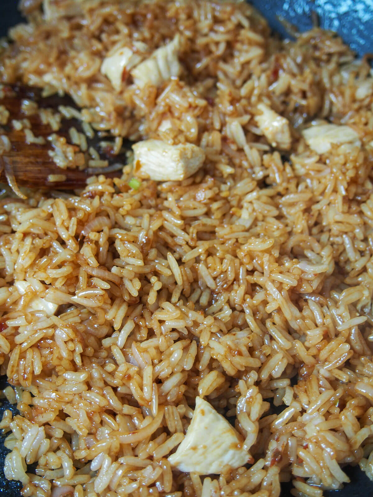 adding kecap manis to fried rice in pan