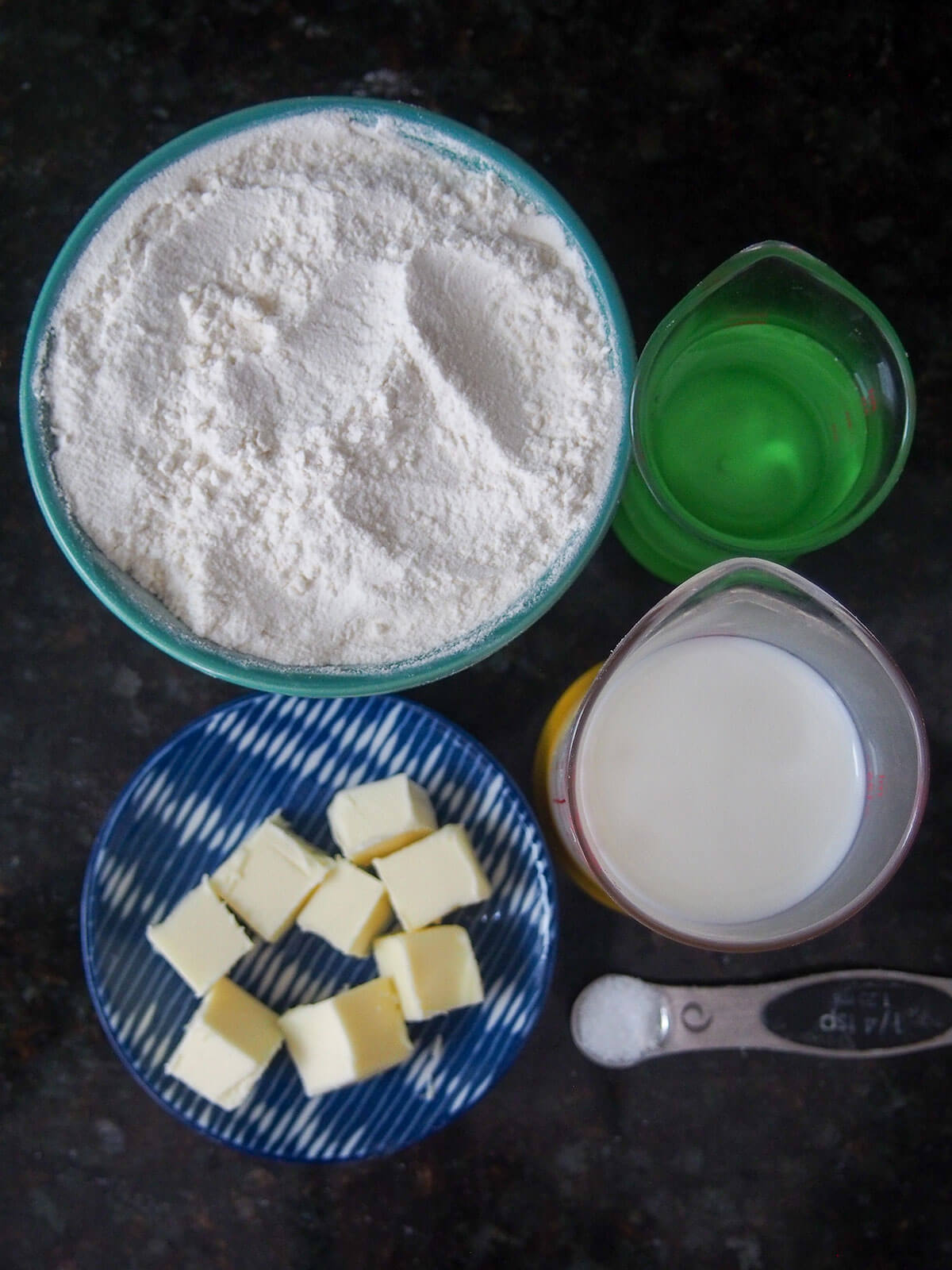 ingredients for Australian damper bread bowl of flour, plate with cubes of butter and measures with milk and water
