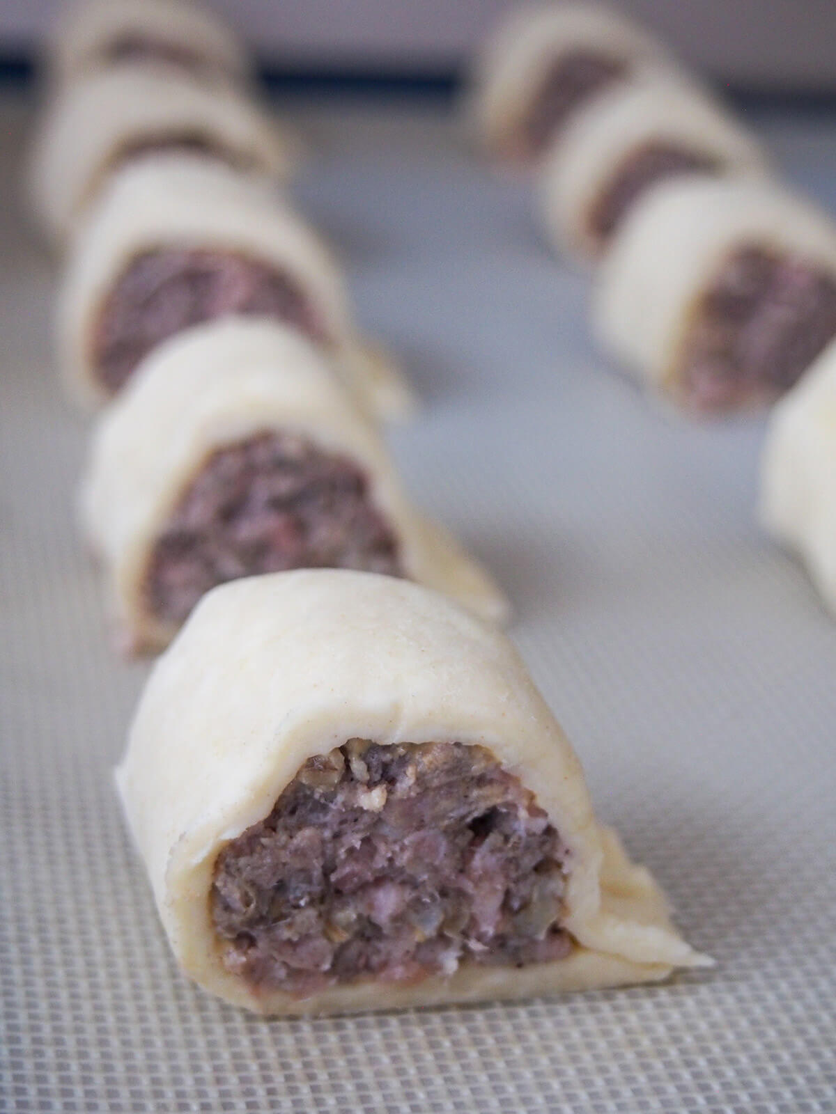 rows of cut haggis sausage rolls on lined baking sheet before baking