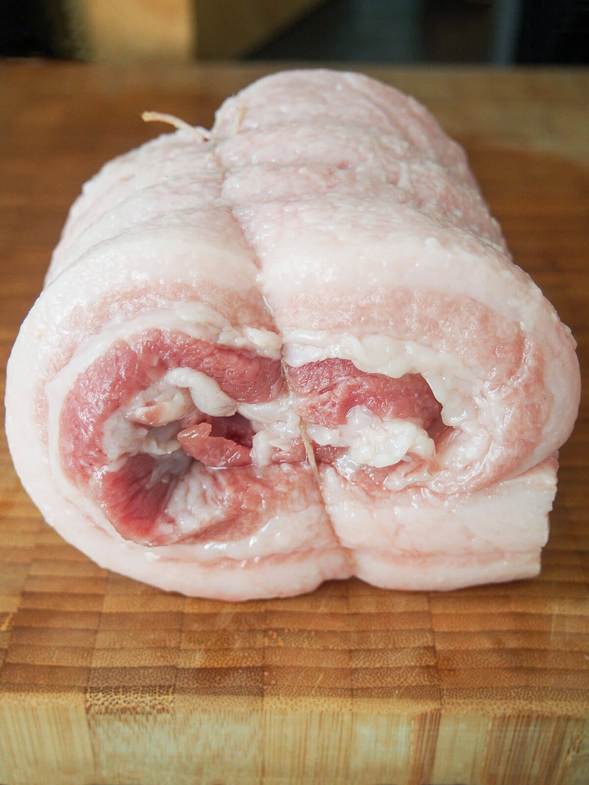 rolled pork belly tied with string on chopping board