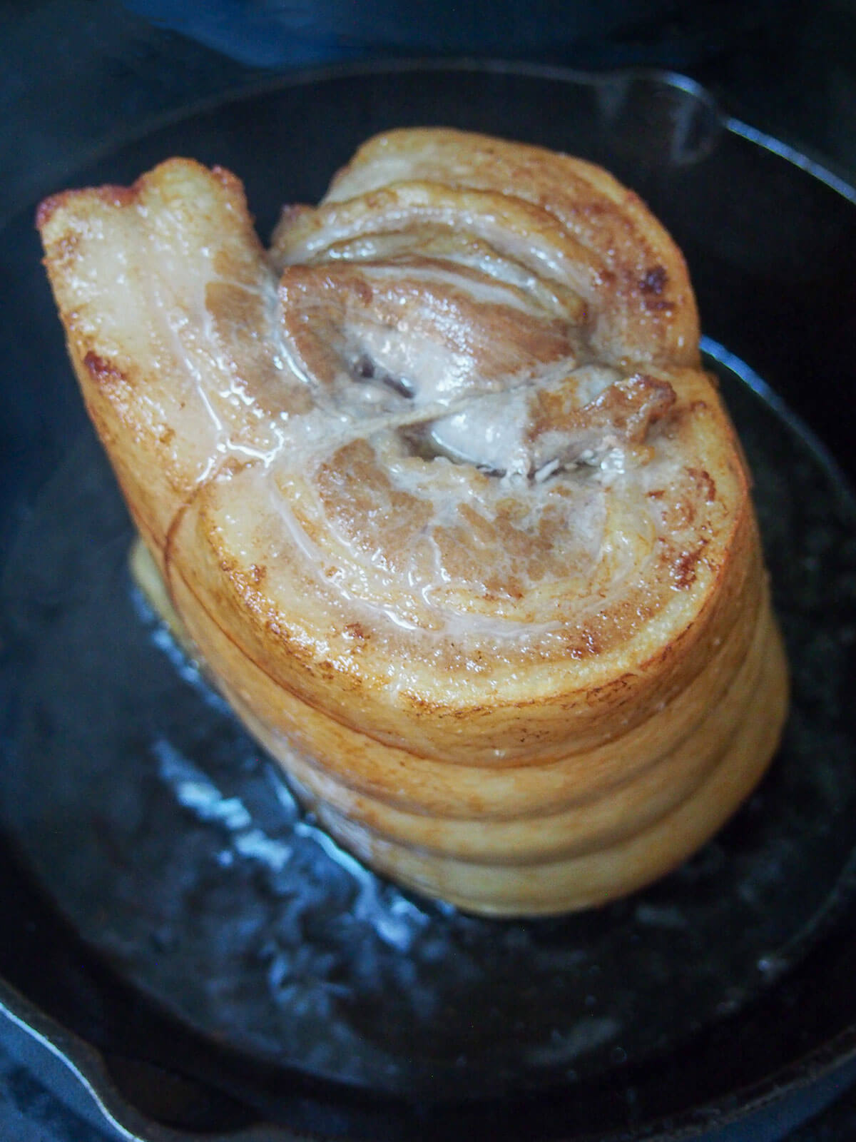 searing the rolled pork belly in a skillet