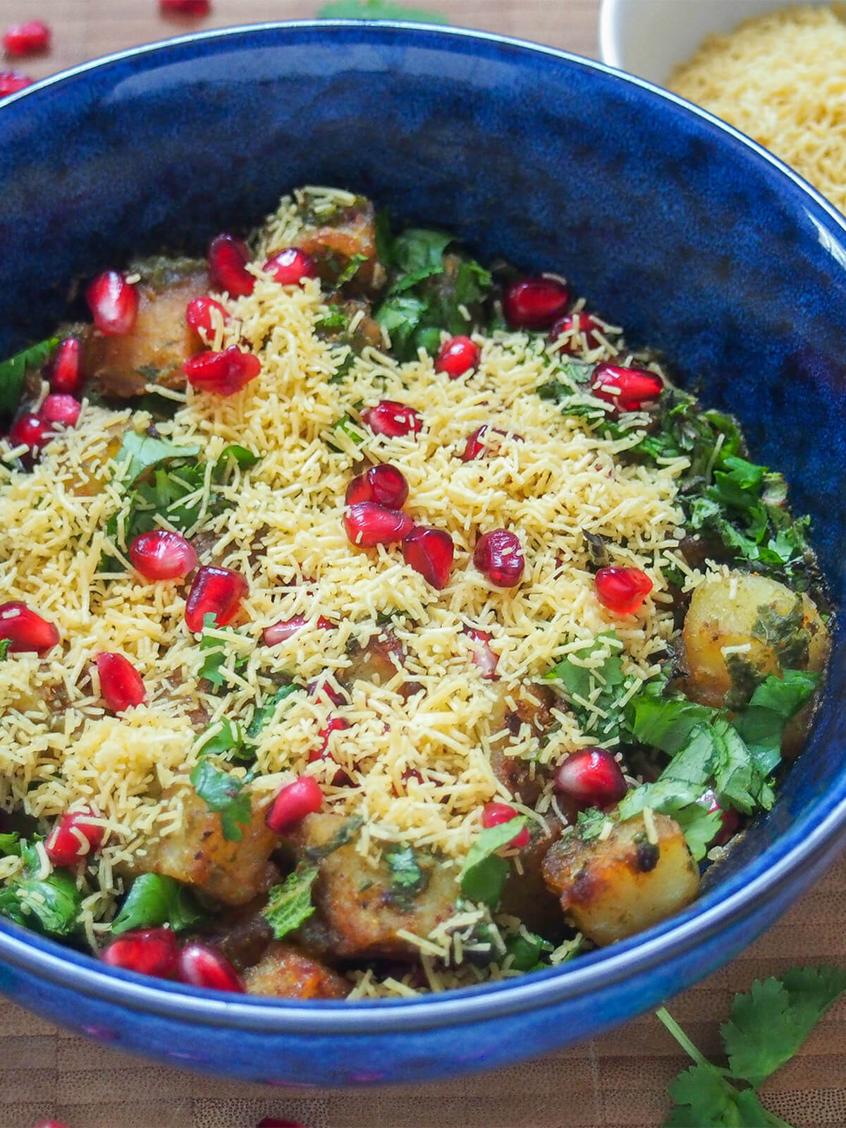 Aloo chaat is a delicious Indian snack combining fried potatoes with spices, chutney, herbs and more. It's easy to make, has tangy and spicy flavors and is addictively good. side view of bowl of aloo chaat