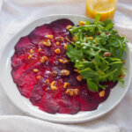 plate of beet carpaccio with jar of dressing behind
