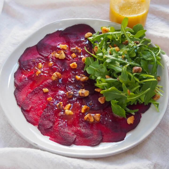 plate of beet carpaccio with jar of dressing behind