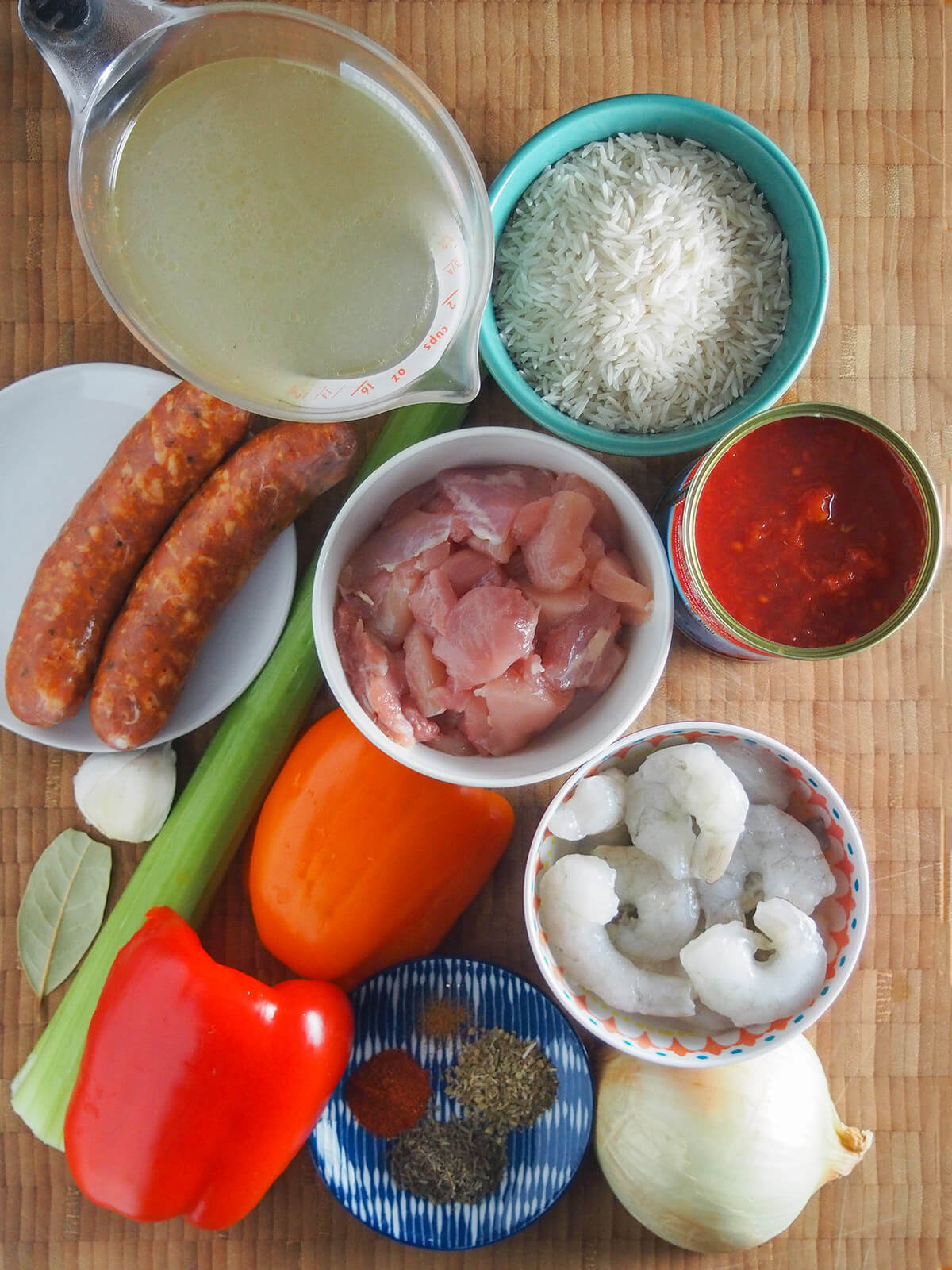 dishes with rice, chicken, shrimp, stock with sausages, pepper, onion, spices and celery around