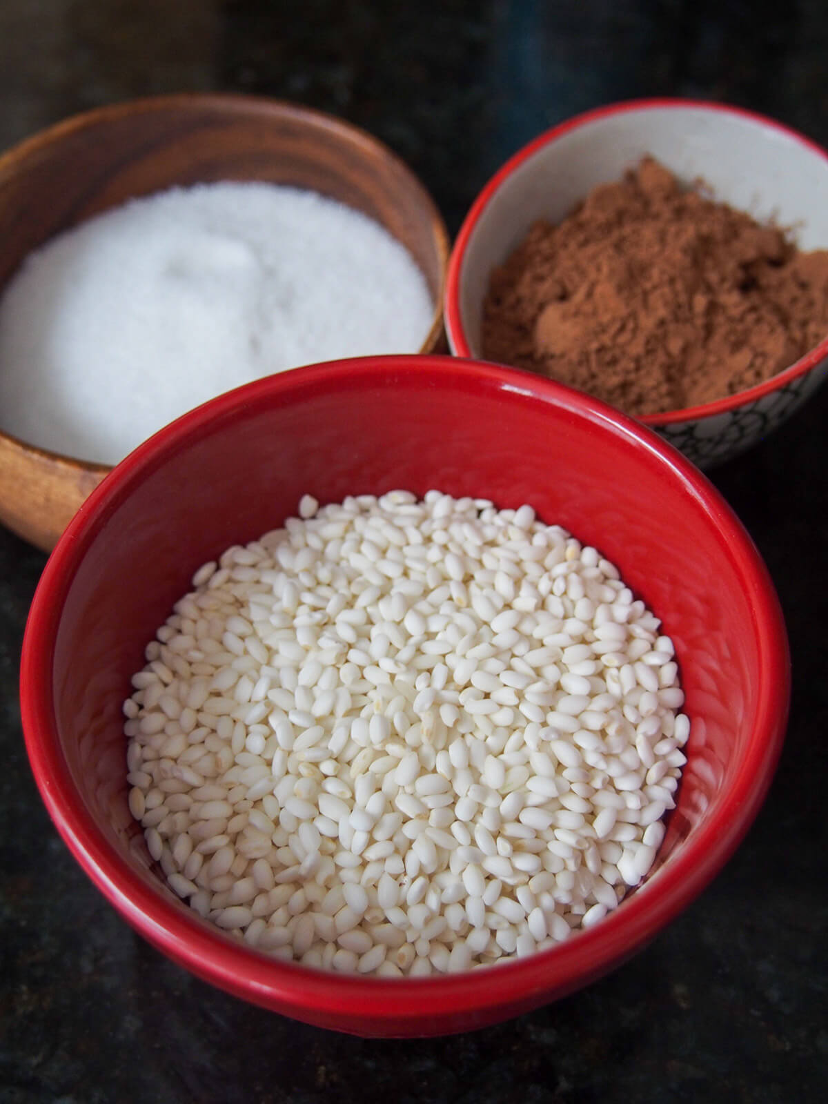 bowl of sweet rice with bowls of sugar and cocoa powder behind