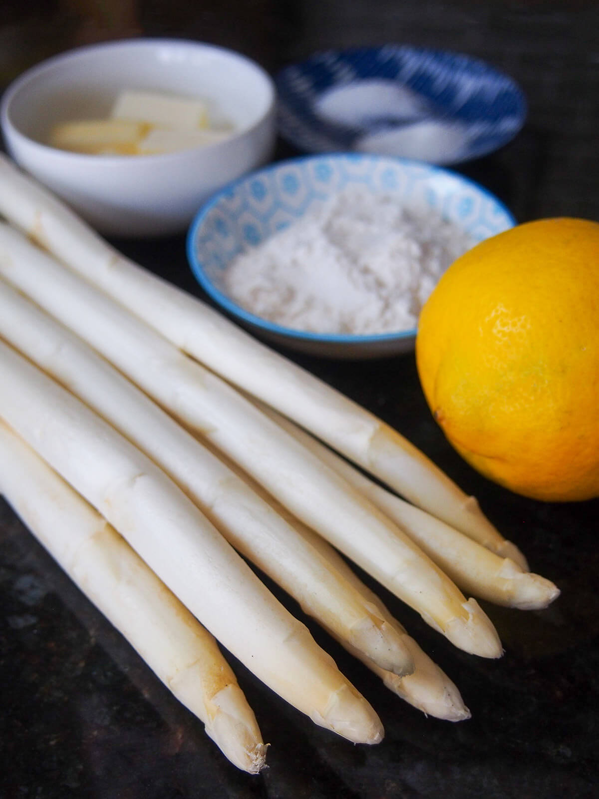 white asparagus bunch with lemon, flour and butter behind