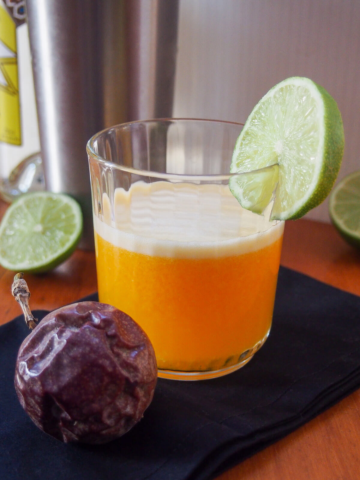 glass of maracuya sour with light catching behind shaker in background