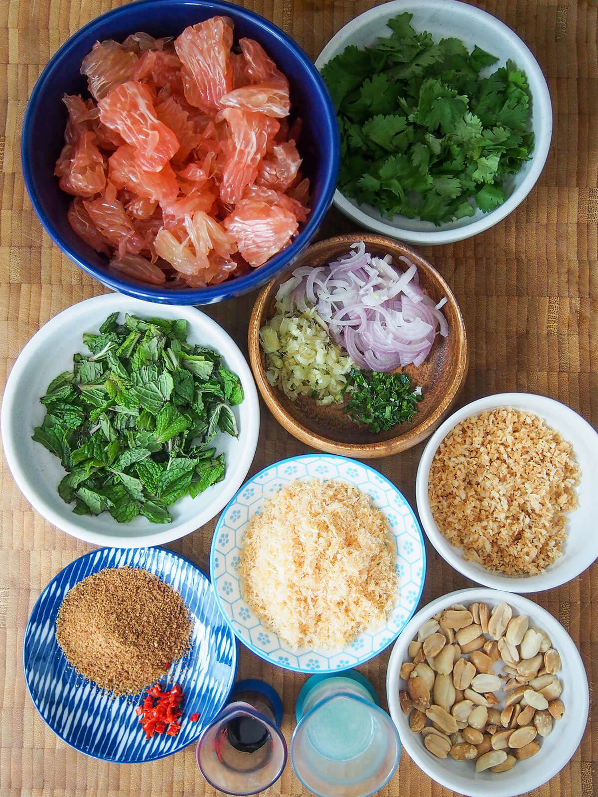 bowls with pomelo chunks, herbs, ground shrimp, nuts