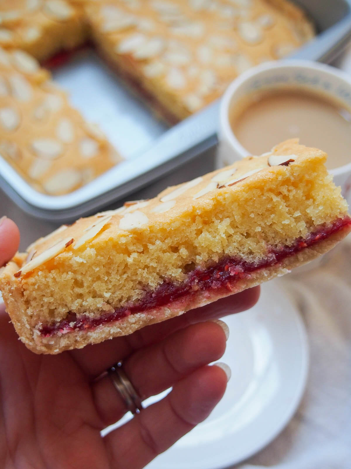holding a piece of Bakewell slice in hand over pan
