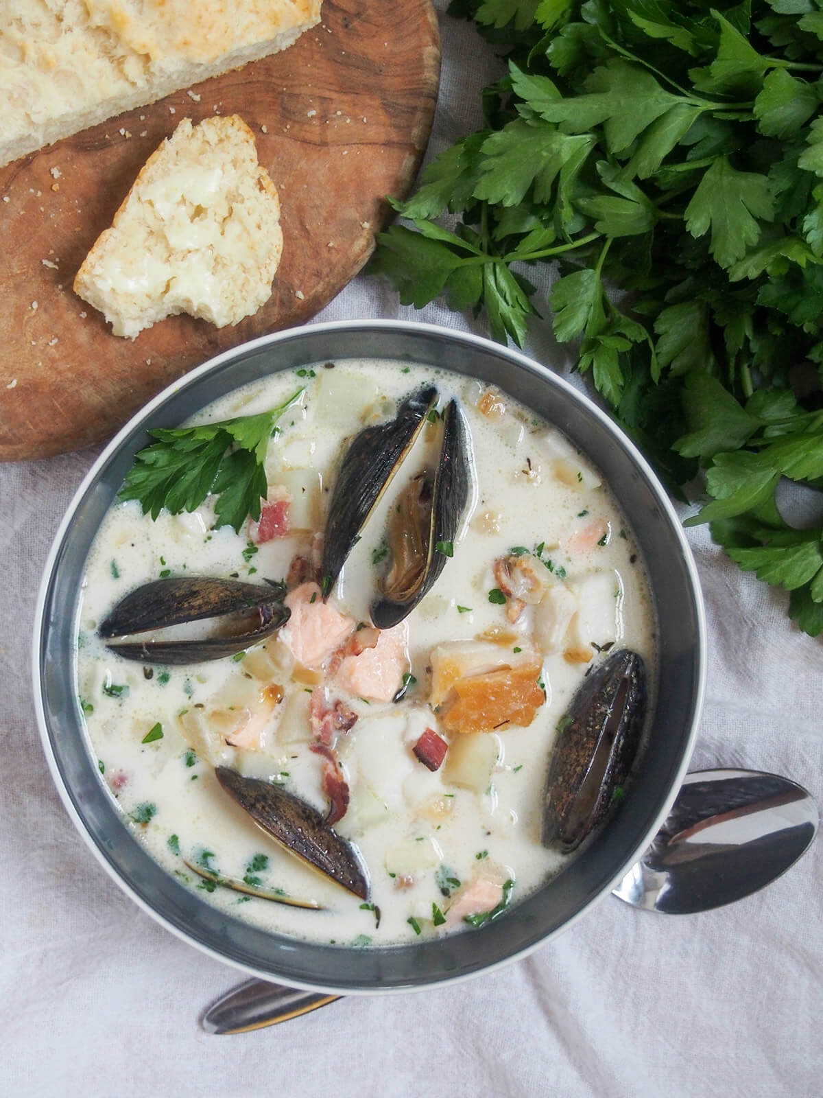 bowl of Irish fish or seafood chowder from overhead with parsley and board with slice of bread above