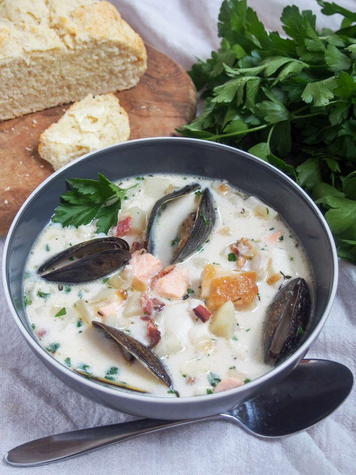side view of bowl of Irish fish or seafood chowder with soda bread behind