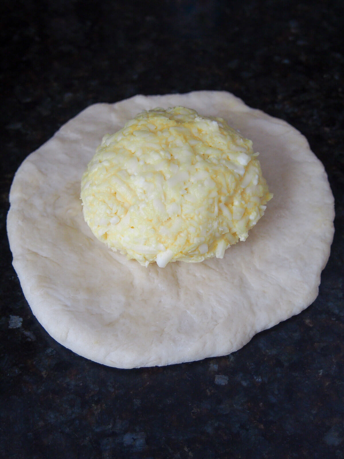 ball of cheese filling on top of flattened dough