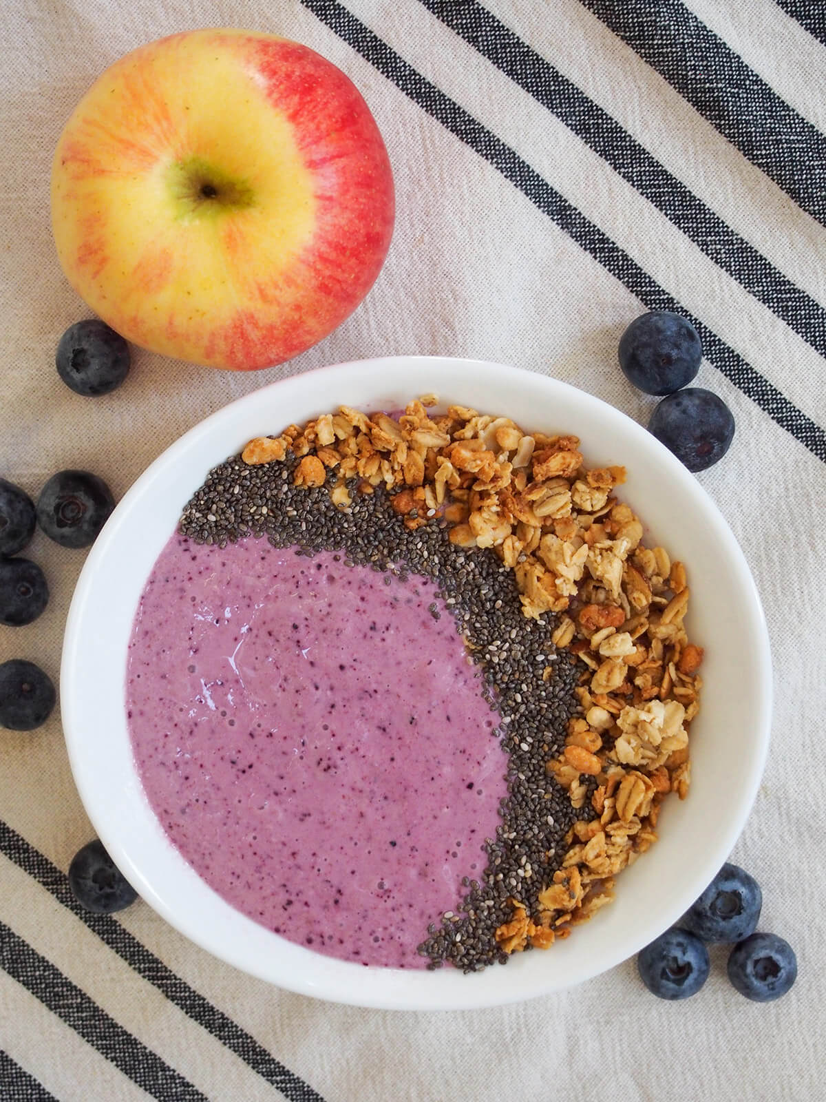 blueberry apple smoothie bowl with apple above bowl and blueberries around