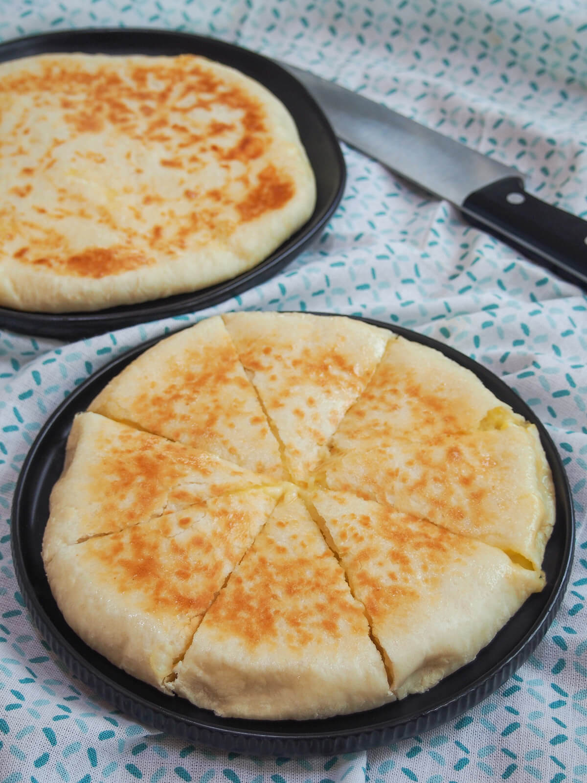 whole imeruli khachapuri cut into pieces with whole one behind