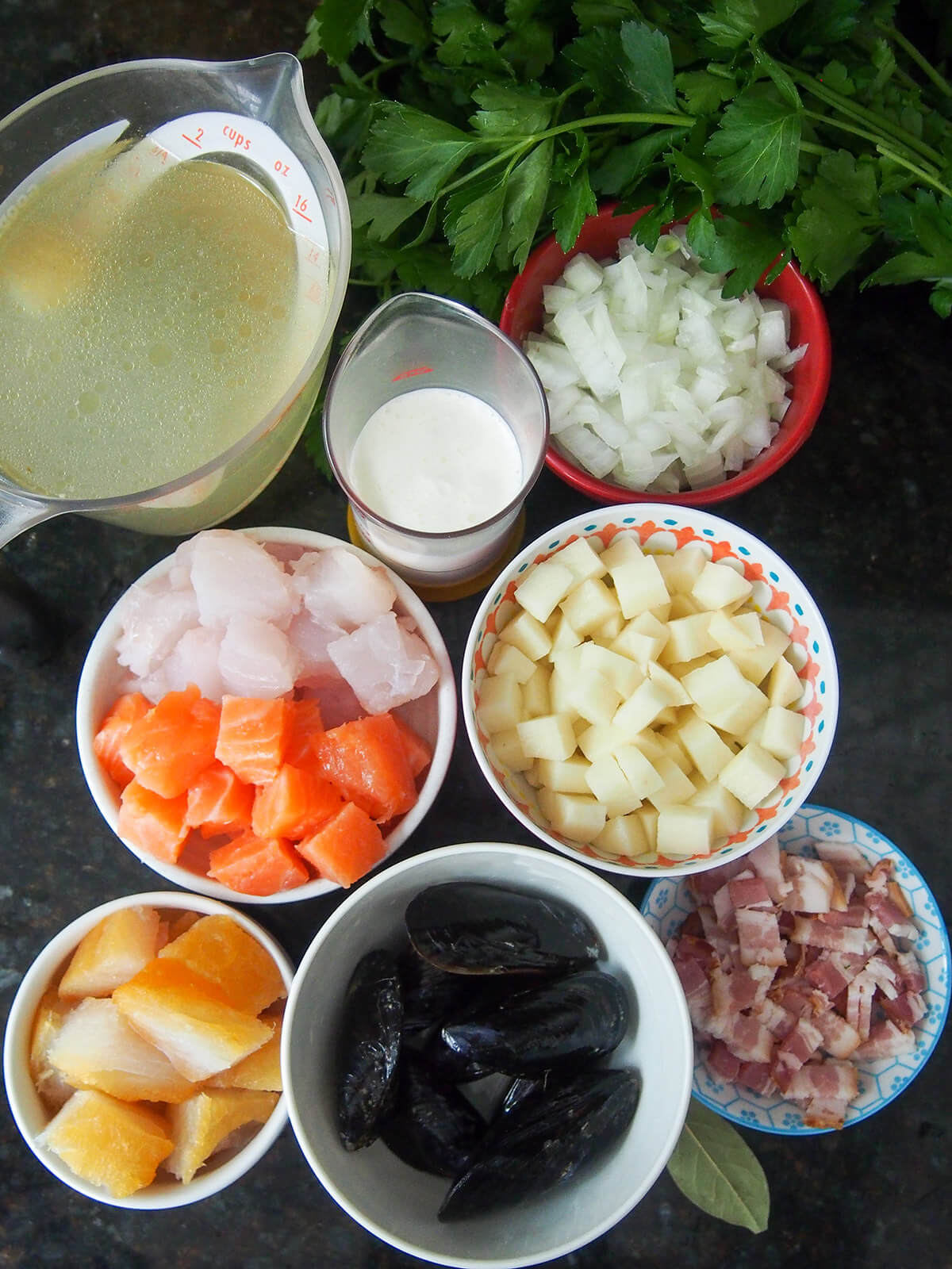 bowls with fish, potatoes, onion, mussels, bacon, stock and cream