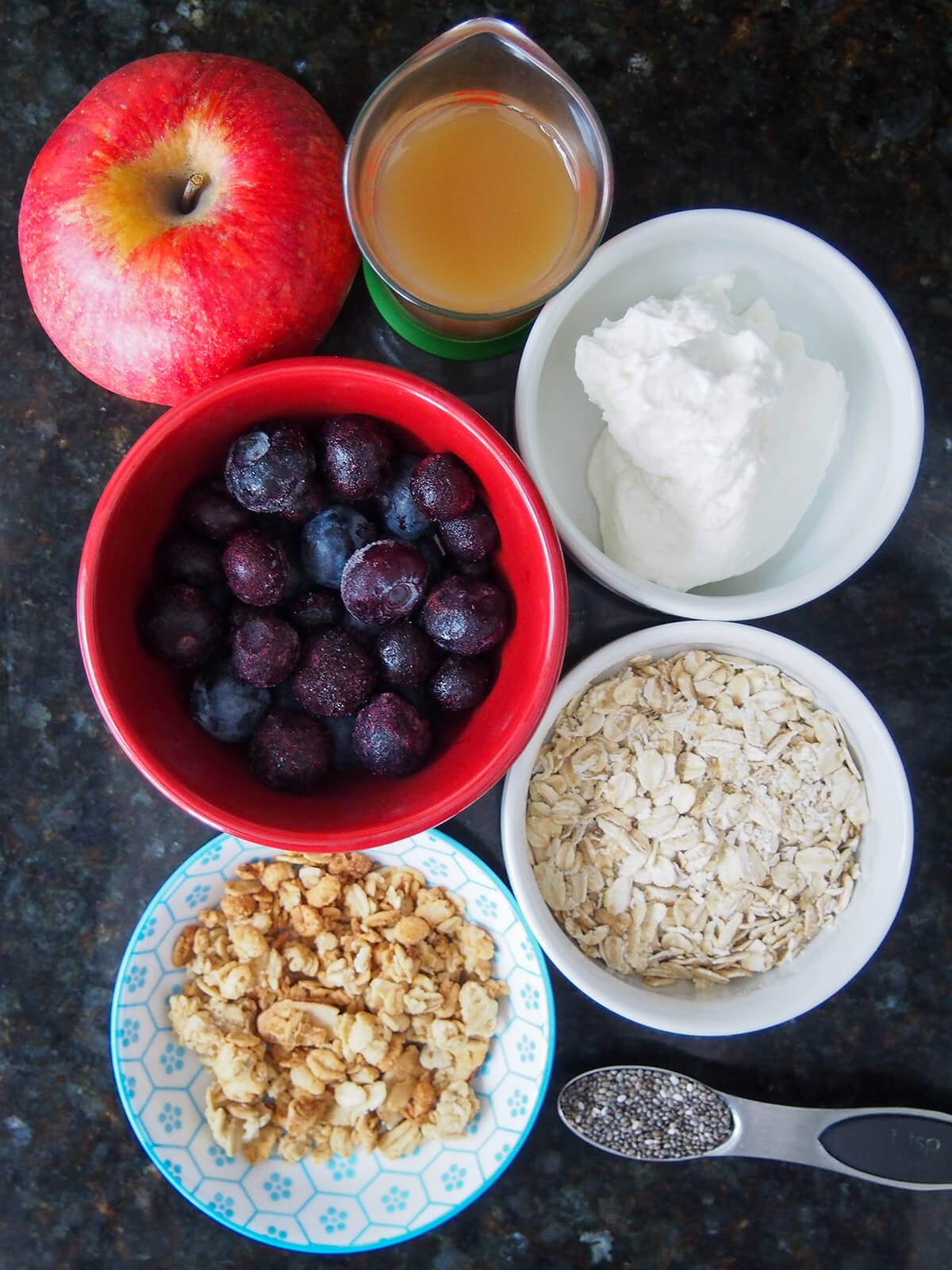bowls with yogurt, blueberries, oats, apple juice and granola with apple above