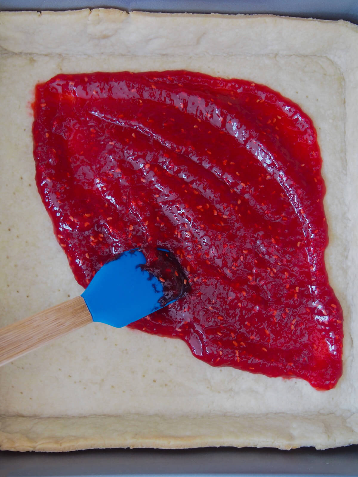 spreading jam on pastry base