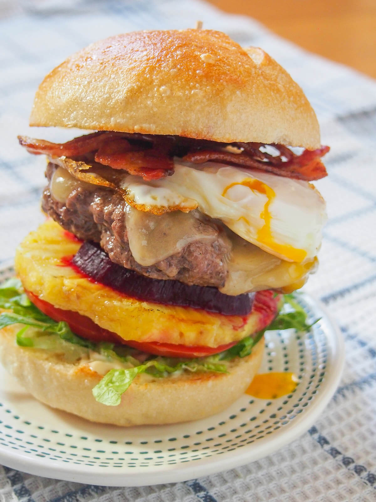 Aussie burger with egg dripping onto plate