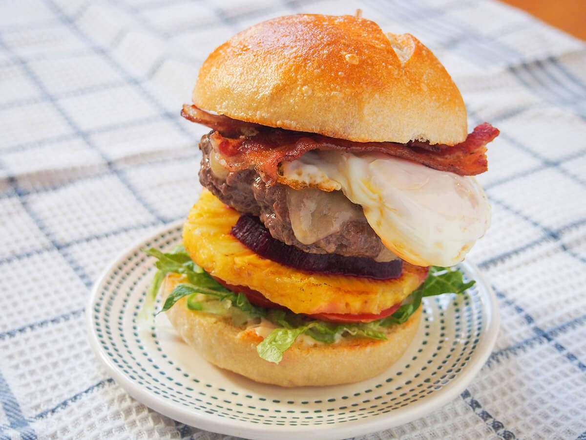 Aussie burger on plate on a white checked cloth
