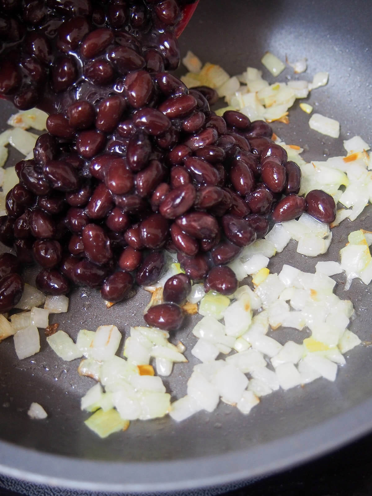 adding black beans to skillet with onion