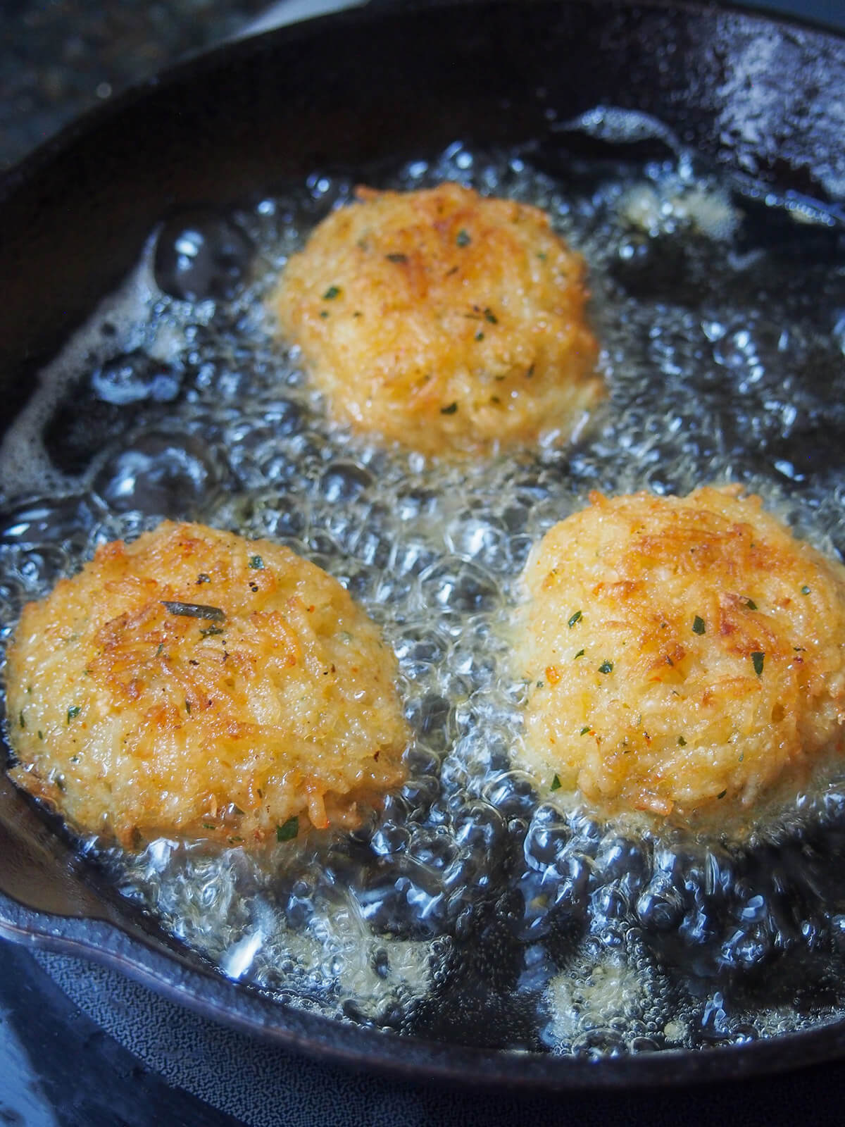 frying second side of rice balls in oil showing crisp top