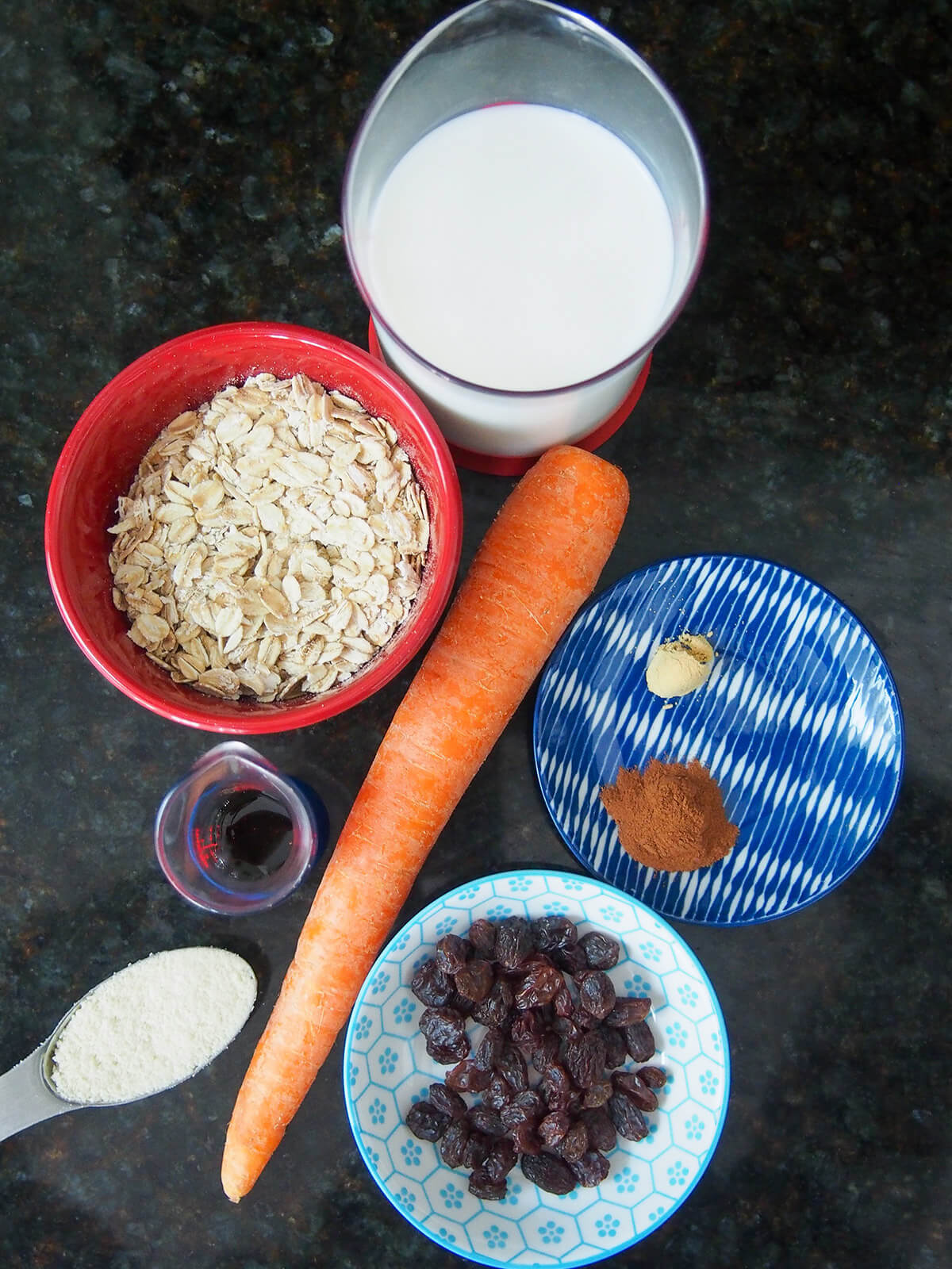 bowl of oats, carrot, dishes with milk, raisins and spices
