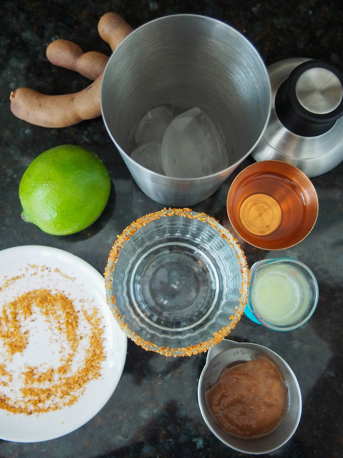 overhead view of measures, glass with chili rim and cocktail shaker with ice in it