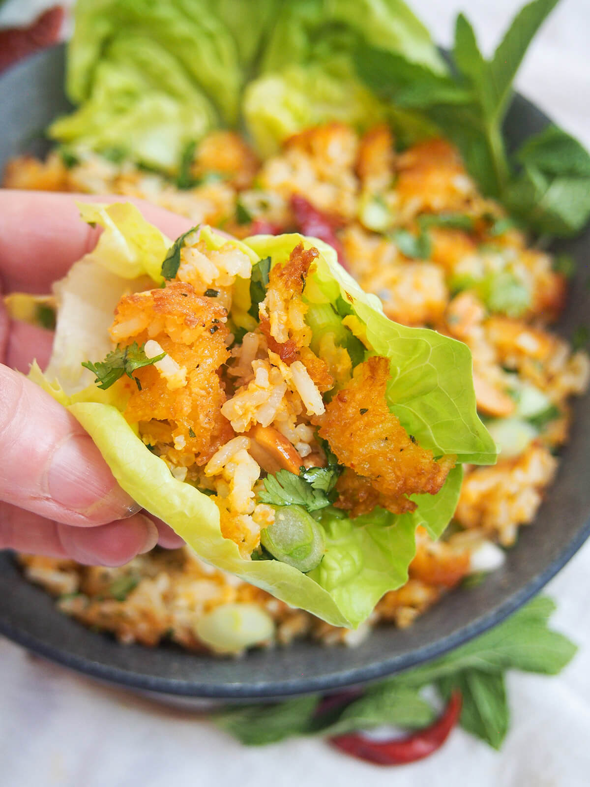 Some nam khao in a piece of lettuce held over bowl
