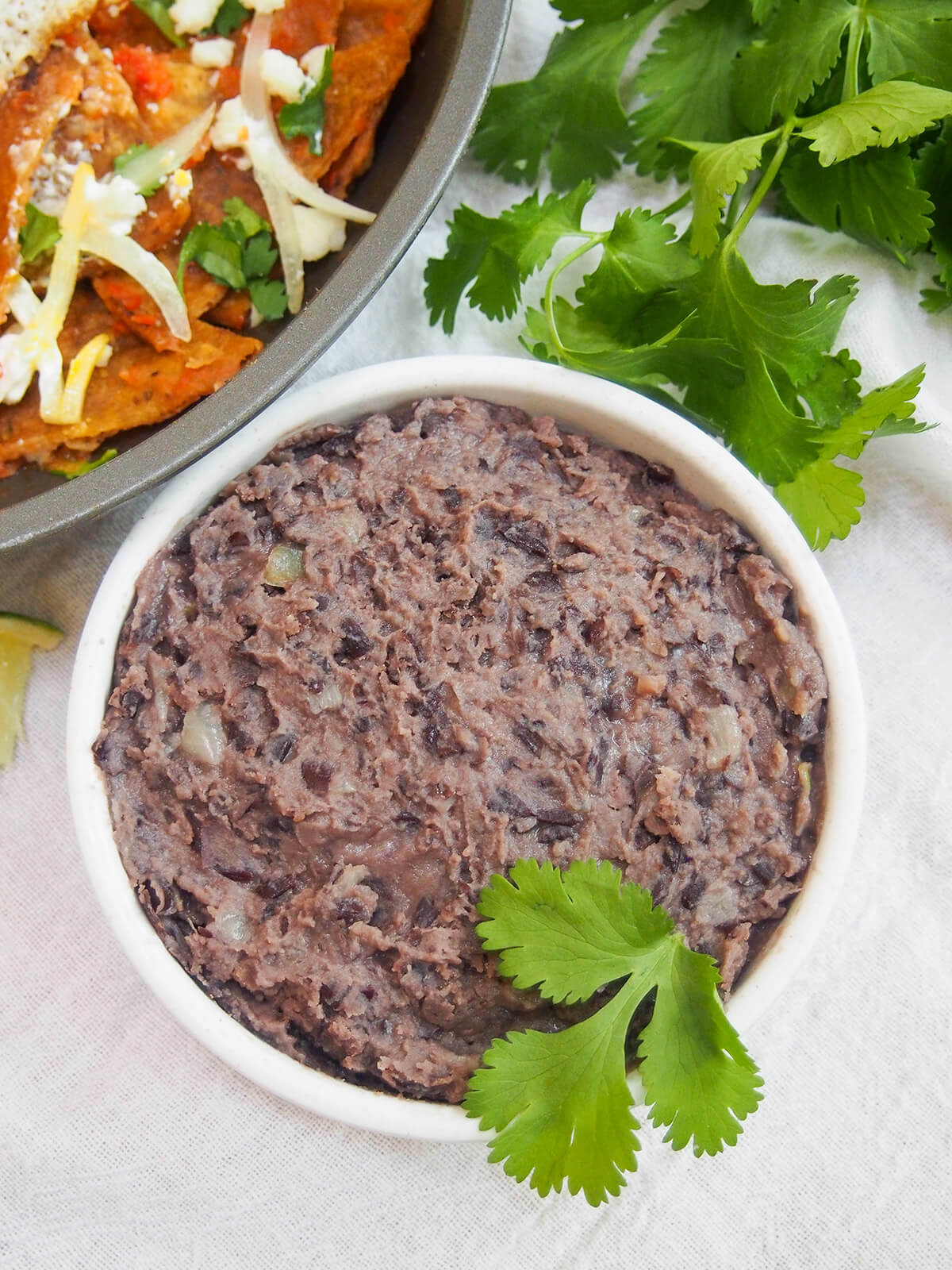 overhead view of dish of refried black beans garnished with cilantro